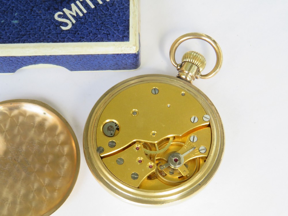 A 1940s Smiths open-face pocket watch with a gold-tone metal case, white Roman numeral dial, and an accompanying textured blue presentation box. View III