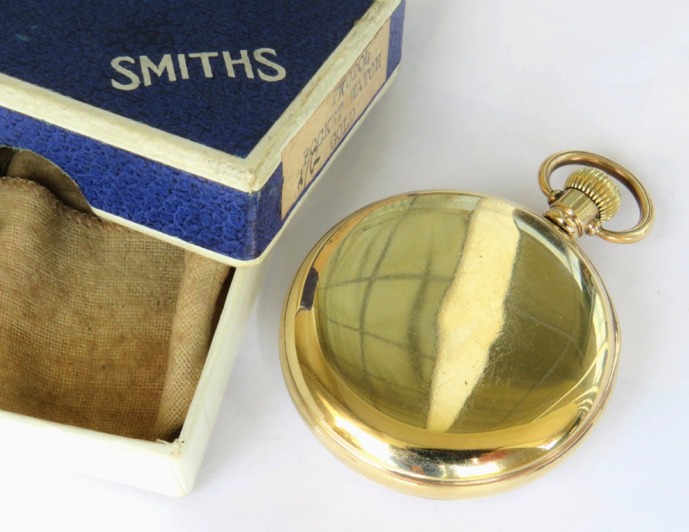 A 1940s Smiths open-face pocket watch with a gold-tone metal case, white Roman numeral dial, and an accompanying textured blue presentation box. View IV
