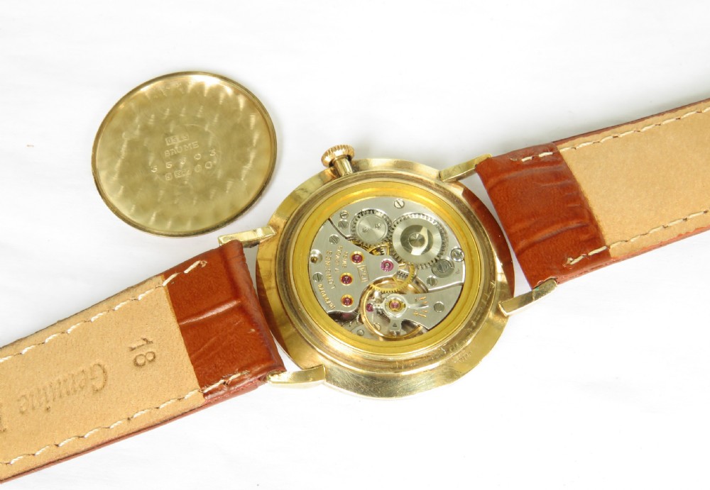 A 1964 gents Longines wristwatch featuring a round 9ct gold case, gold-tone sunburst dial with slim baton markers, sub-second dial at six oclock, and a brown leather strap. View III