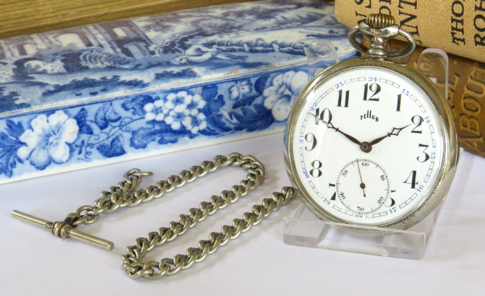 A 1930s Tellus open-face pocket watch featuring a white dial with black Arabic numerals and a silver-tone curb link chain with a T-bar.
