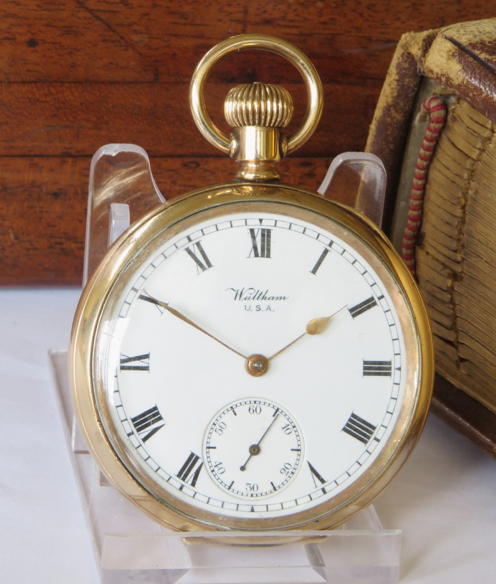 An open-face gold Waltham Traveler pocket watch featuring a white enamel dial with black Roman numerals and a subsidiary seconds dial. View II