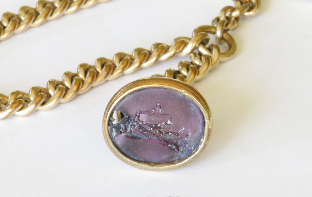 An antique rolled gold curb link Albert watch chain featuring a T-bar fastener, swivel hook, and an oval purple glass fob carved with a haymaking scene intaglio. View III