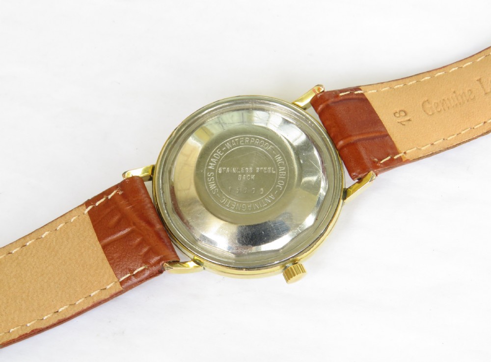 A 1960s Avia DayTyme gents wristwatch featuring a gold-plated case, champagne dial with day and date apertures, and a brown leather strap. View IV