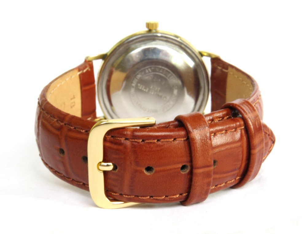 A 1960s Avia DayTyme gents wristwatch featuring a gold-plated case, champagne dial with day and date apertures, and a brown leather strap. View V
