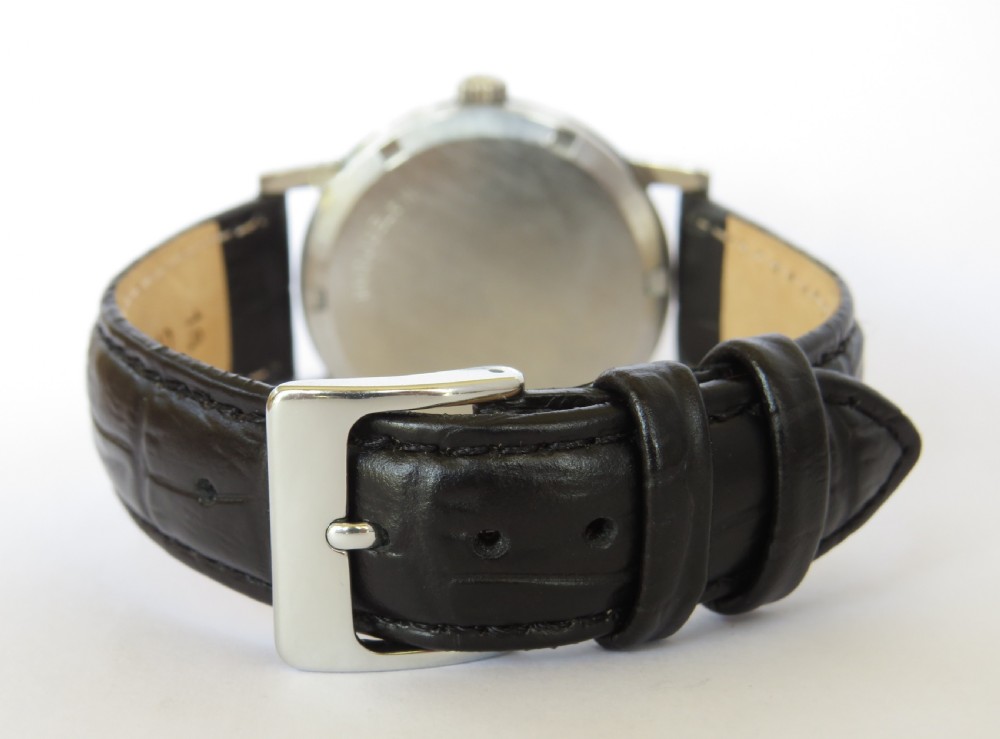 A 1970s gents Omega Geneve wristwatch featuring a round silver-toned dial, black baton hour markers, and a black leather strap. View V