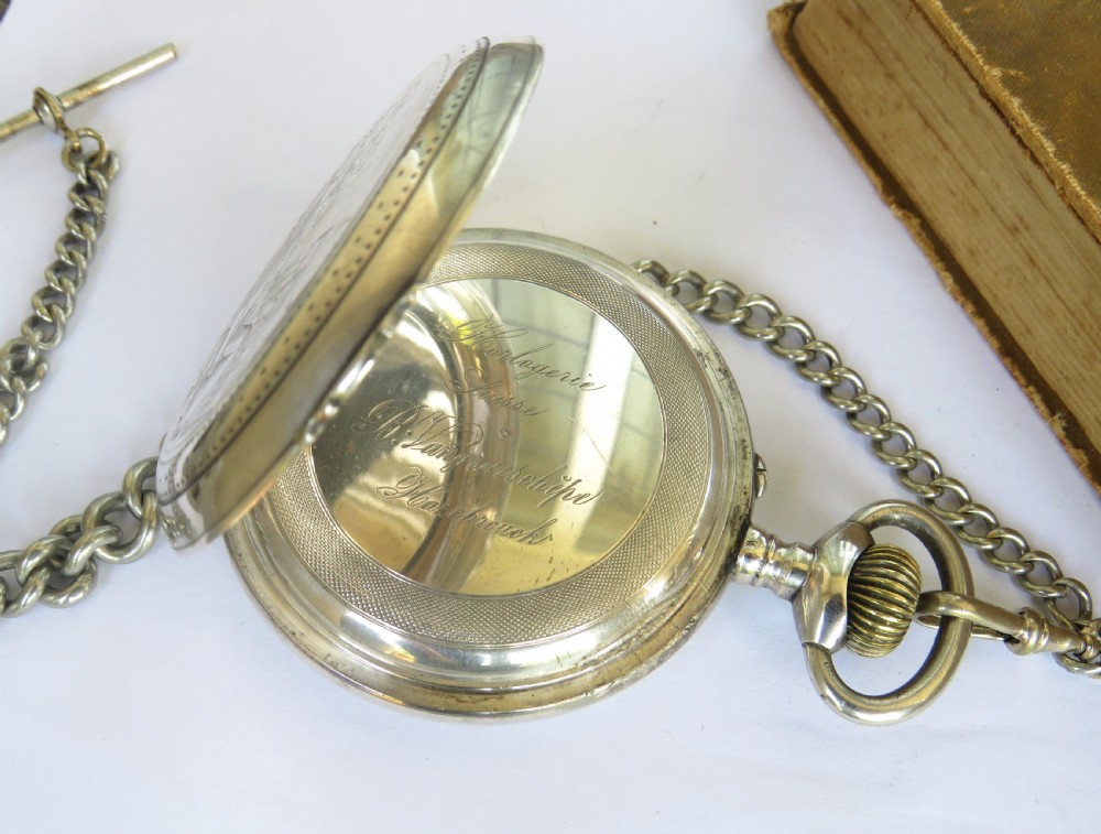 An antique open-face Goliath pocket watch with a white enamel dial, black Roman numerals, subsidiary seconds dial, and attached metal T-bar chain. View III