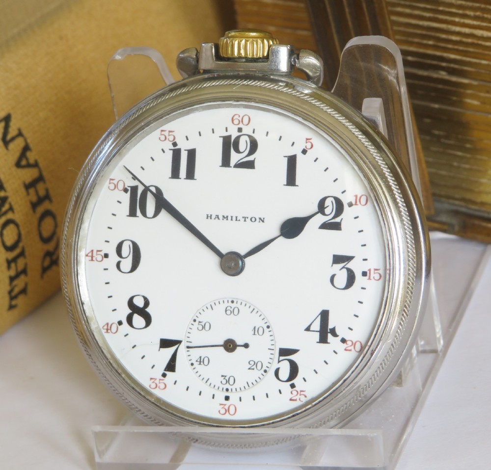 A vintage Hamilton open-face pocket watch featuring a white dial, bold black Arabic numerals, a sub-seconds dial, and a gold-tone crown.