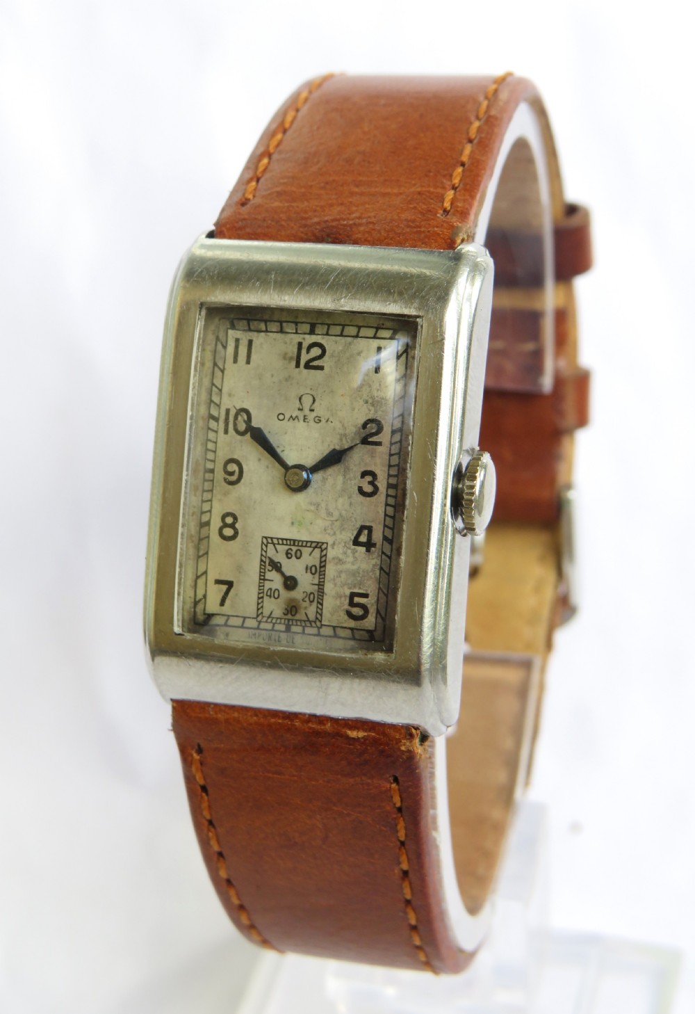 A 1930s rectangular Omega gents wristwatch featuring a silver-tone case, aged cream dial with Arabic numerals, sub-seconds dial, and a tan leather strap.