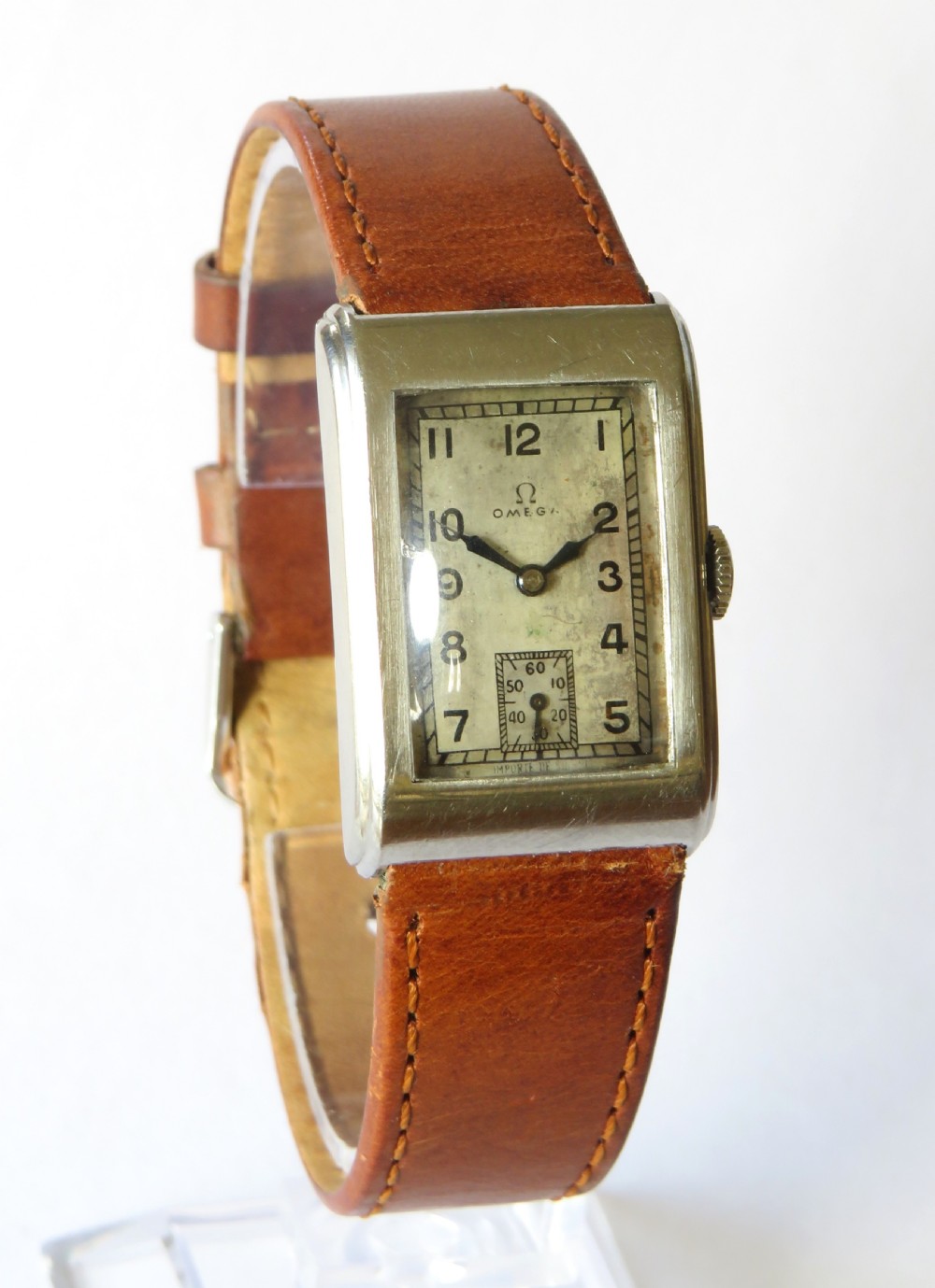 A 1930s rectangular Omega gents wristwatch featuring a silver-tone case, aged cream dial with Arabic numerals, sub-seconds dial, and a tan leather strap. View II
