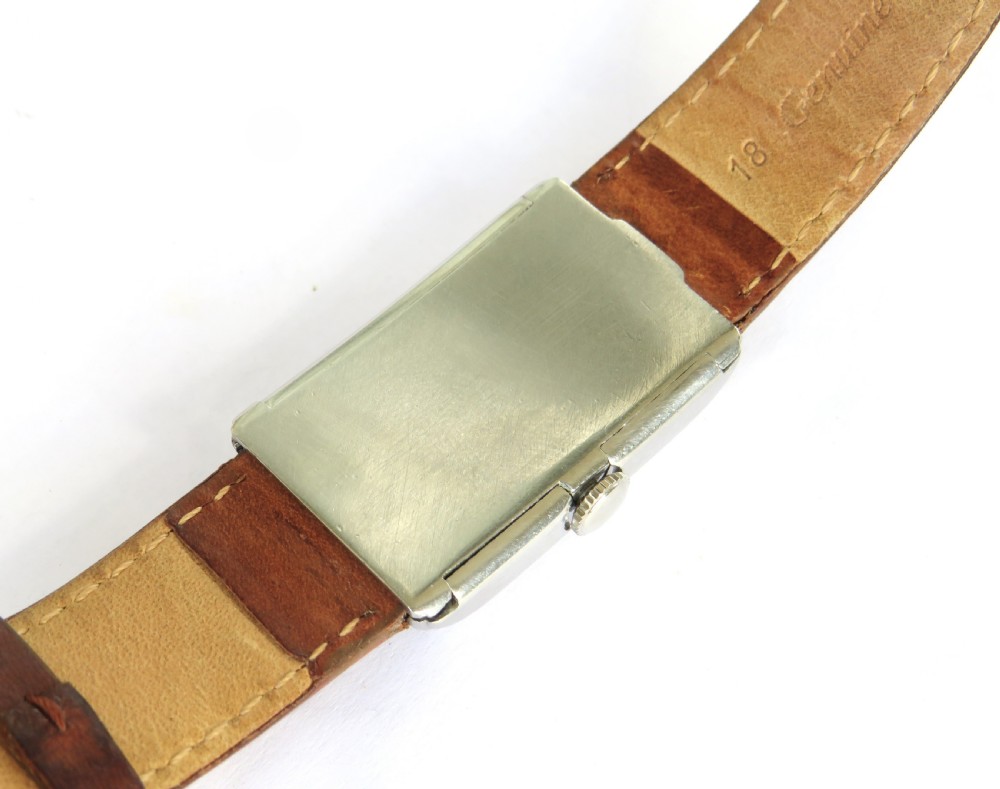 A 1930s rectangular Omega gents wristwatch featuring a silver-tone case, aged cream dial with Arabic numerals, sub-seconds dial, and a tan leather strap. View IV
