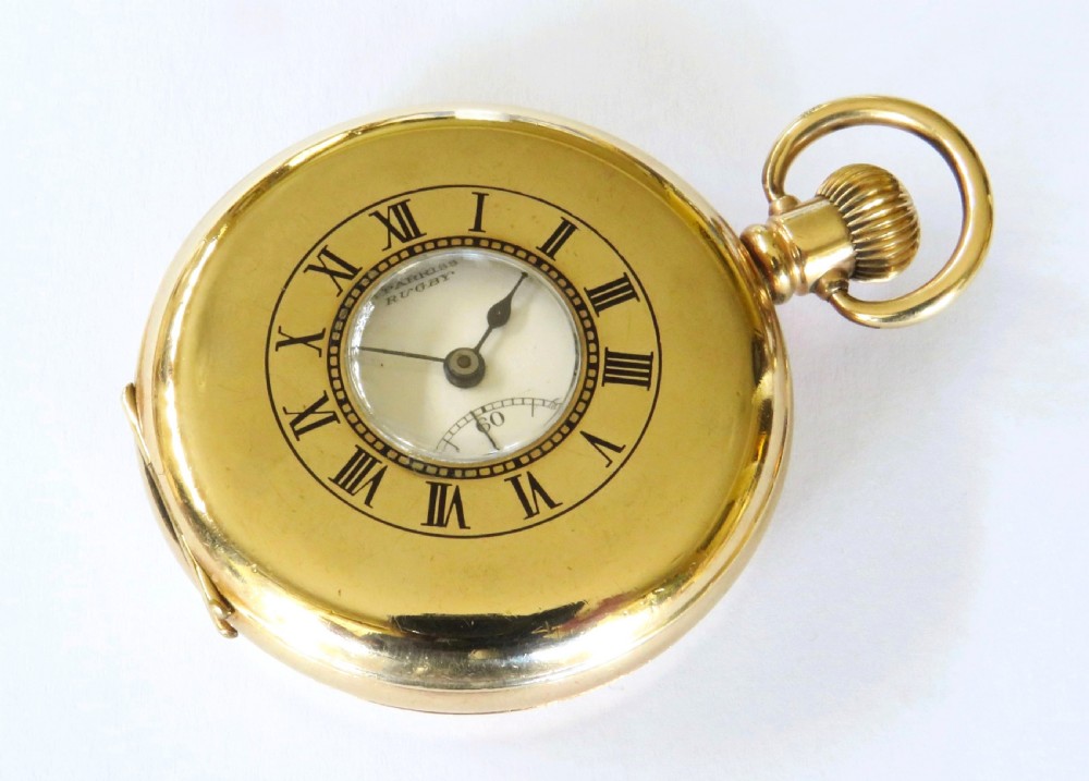 A 1930s gold-toned half hunter pocket watch displayed open, revealing a white dial with black Roman numerals and a subsidiary seconds dial. View III