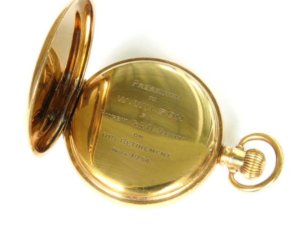 A 1930s gold-toned half hunter pocket watch displayed open, revealing a white dial with black Roman numerals and a subsidiary seconds dial. View IV