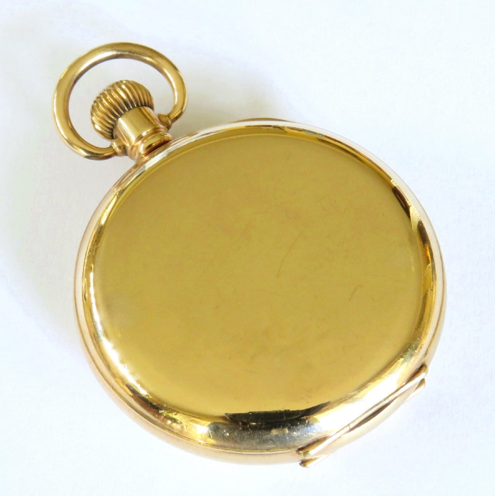 A 1930s gold-toned half hunter pocket watch displayed open, revealing a white dial with black Roman numerals and a subsidiary seconds dial. View VI