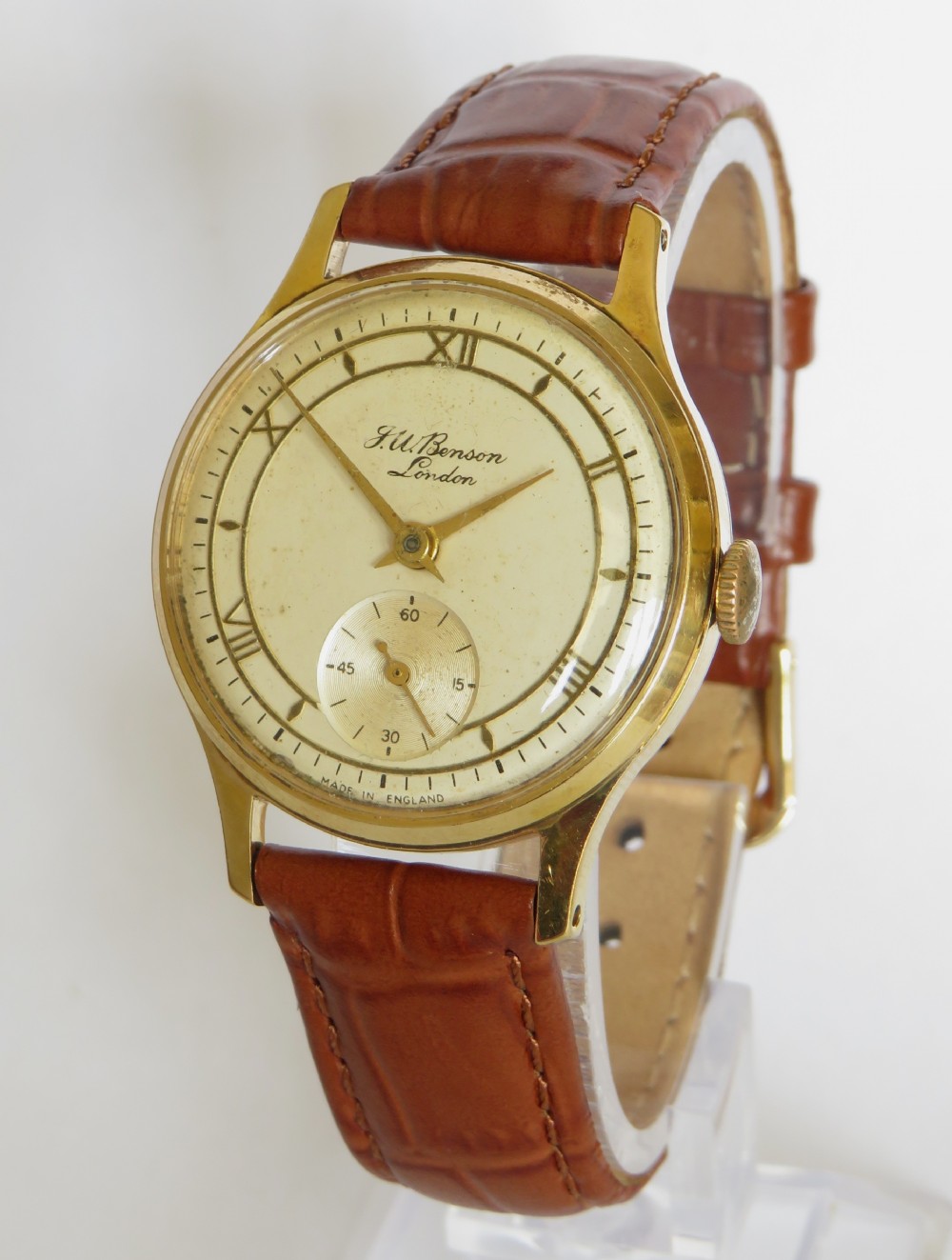 A 1950s gents J W Benson wristwatch with a gold-plated case, cream dial featuring Roman numerals and sub-seconds register, and a brown leather strap.