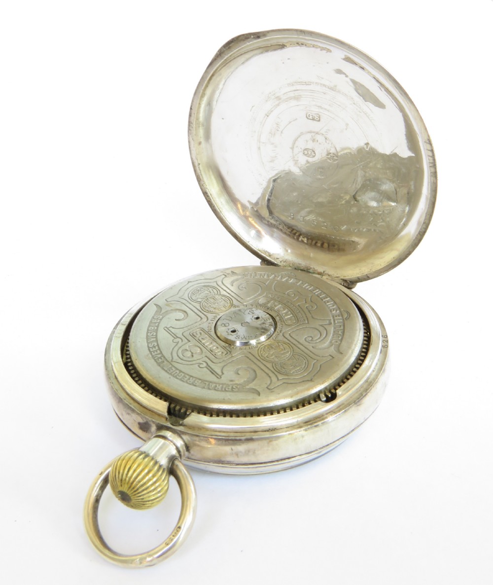 An antique Swiss pocket watch featuring a white enamel dial with Arabic numerals, silver leaf motifs, and a visible brass open escapement at the base. View IV