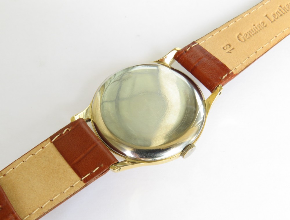 A gents gold-plated circular wristwatch with a cream dial, gold Arabic numerals, red-tipped second hand, and brown leather strap. View IV