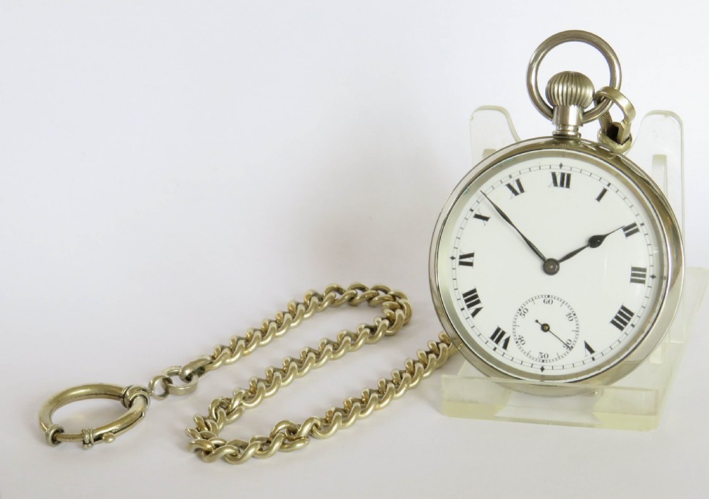 An open face silver pocket watch featuring black Roman numerals on a white enamel dial with an attached brass curb chain. View II