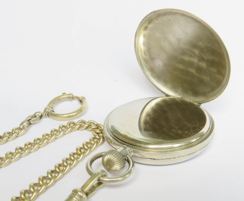An open face silver pocket watch featuring black Roman numerals on a white enamel dial with an attached brass curb chain. View IV