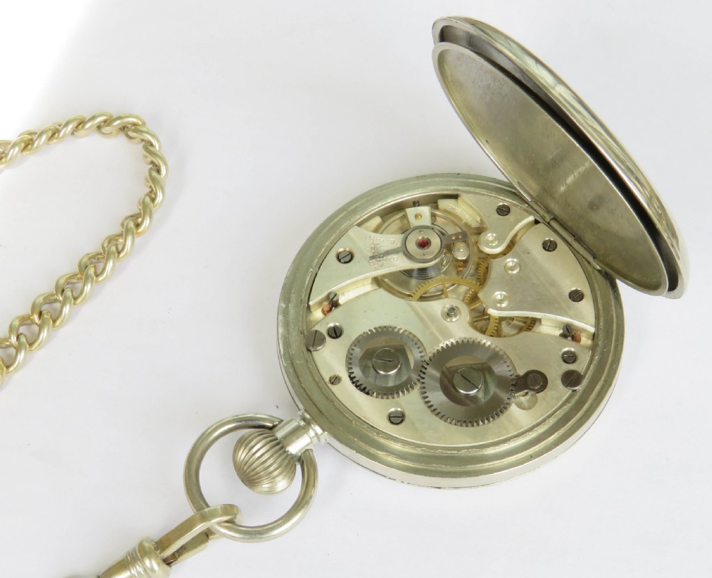An open face silver pocket watch featuring black Roman numerals on a white enamel dial with an attached brass curb chain. View V