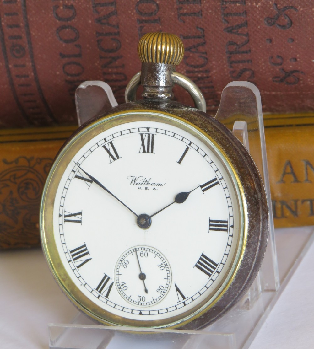 An open-face 1915 Waltham pocket watch featuring a white enamel dial with black Roman numerals, a sub-seconds dial, and a brass winding crown.