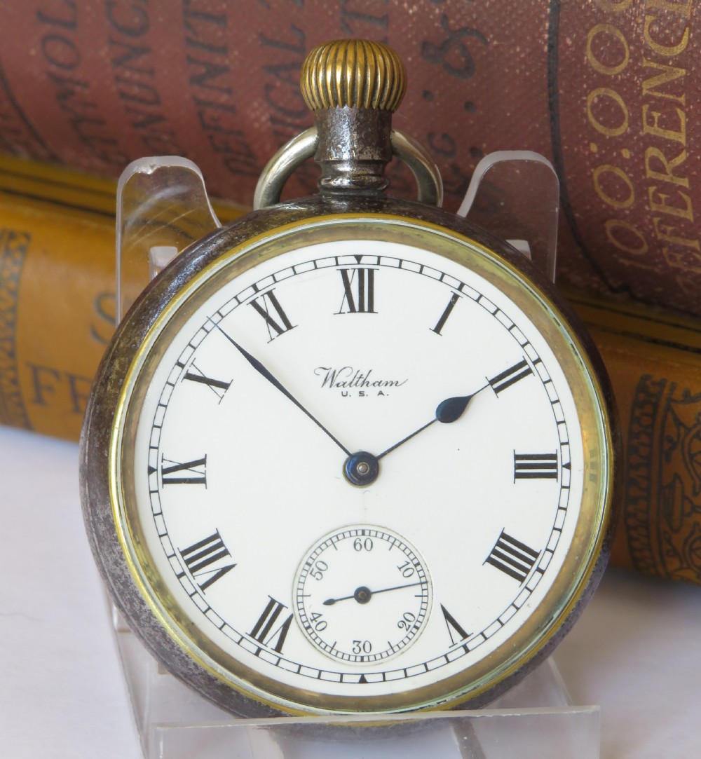 An open-face 1915 Waltham pocket watch featuring a white enamel dial with black Roman numerals, a sub-seconds dial, and a brass winding crown. View II