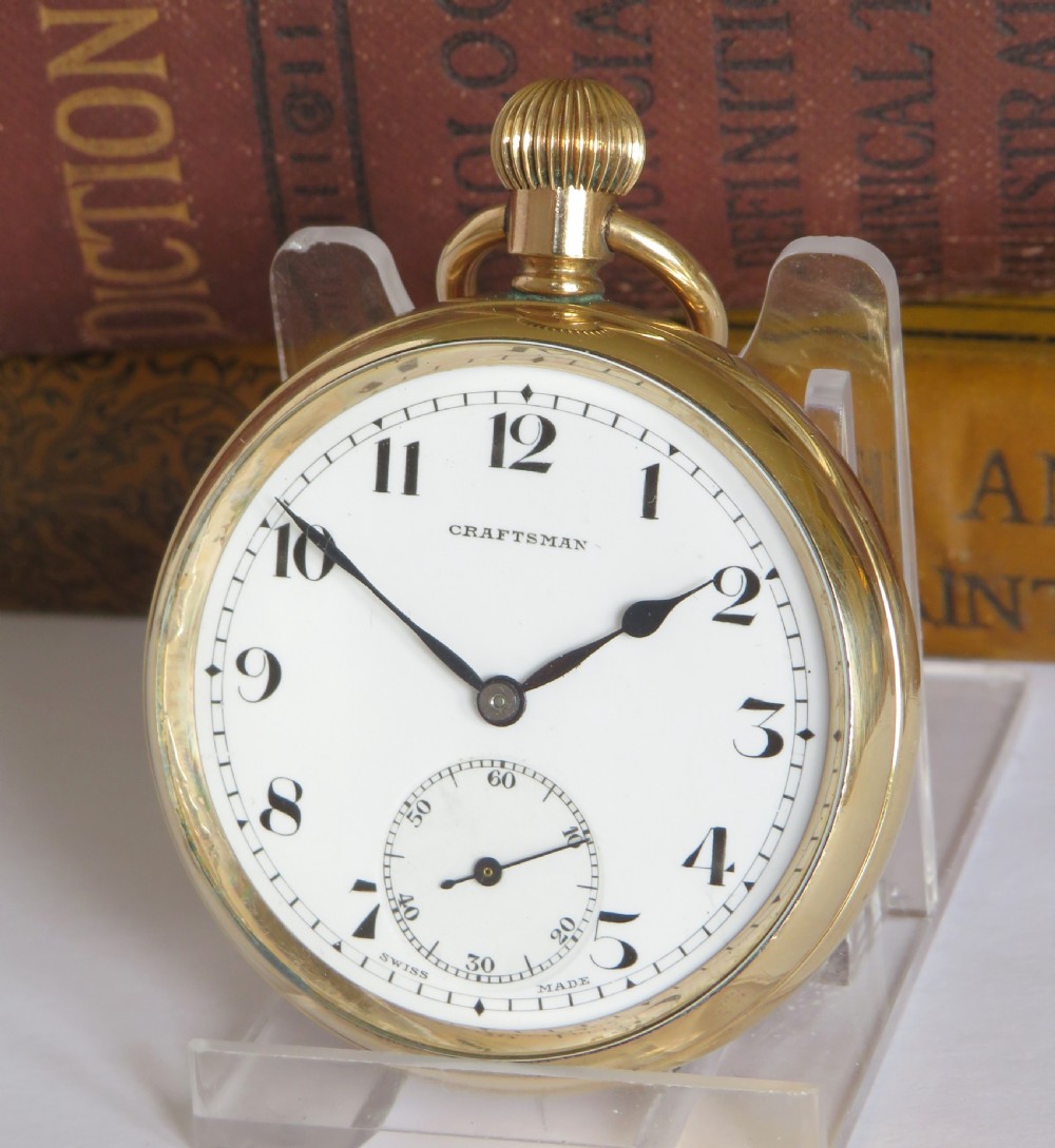A 1930s gold-toned open-face pocket watch featuring a white dial, bold black Arabic numerals, and a small subsidiary seconds dial at the bottom.
