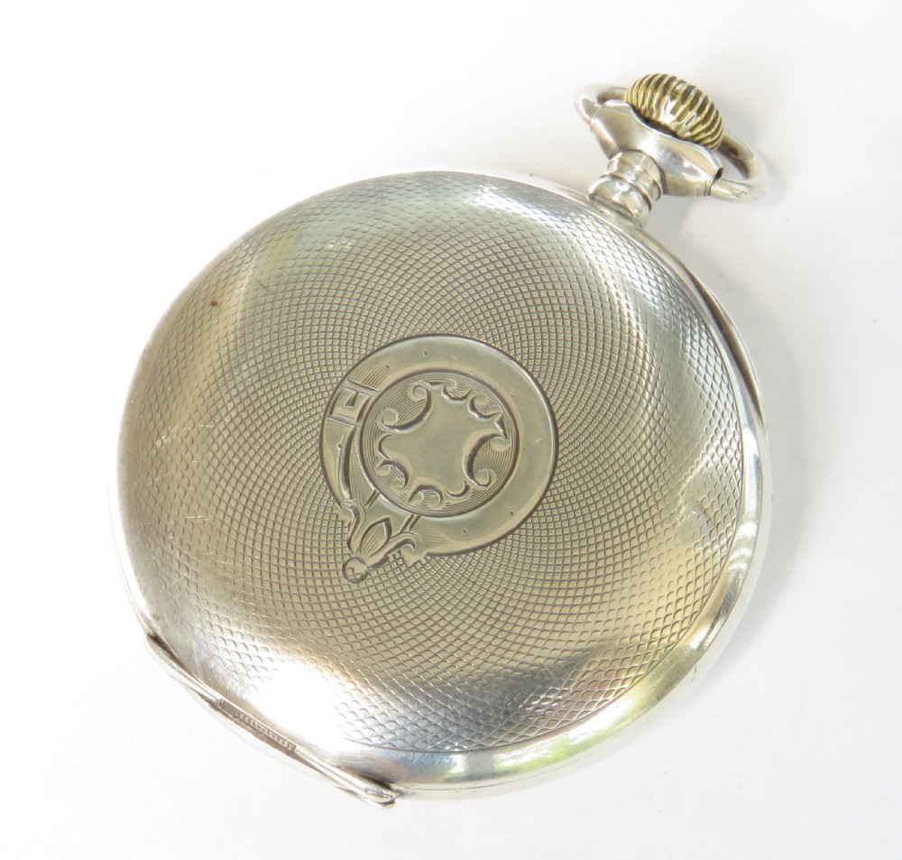 An open-face silver pocket watch featuring a white enamel dial with black Arabic numerals and a small sub-seconds dial at six oclock. View VI