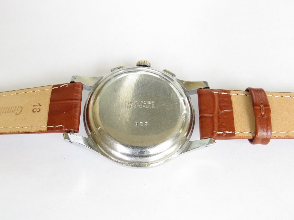 A 1950s vintage chronograph wristwatch featuring a cream dial with two sub-dials, a silver-tone metal case, and a brown leather strap. View III