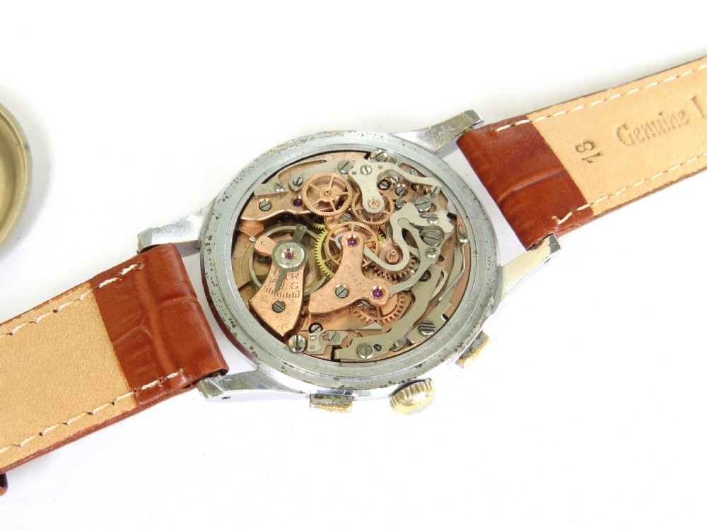 A 1950s vintage chronograph wristwatch featuring a cream dial with two sub-dials, a silver-tone metal case, and a brown leather strap. View IV