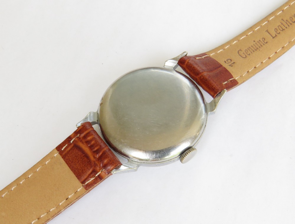 A mid-20th-century gents Smiths wristwatch featuring a champagne dial with Roman numerals, subsidiary seconds dial, silver-tone case, and tan leather strap. View IV