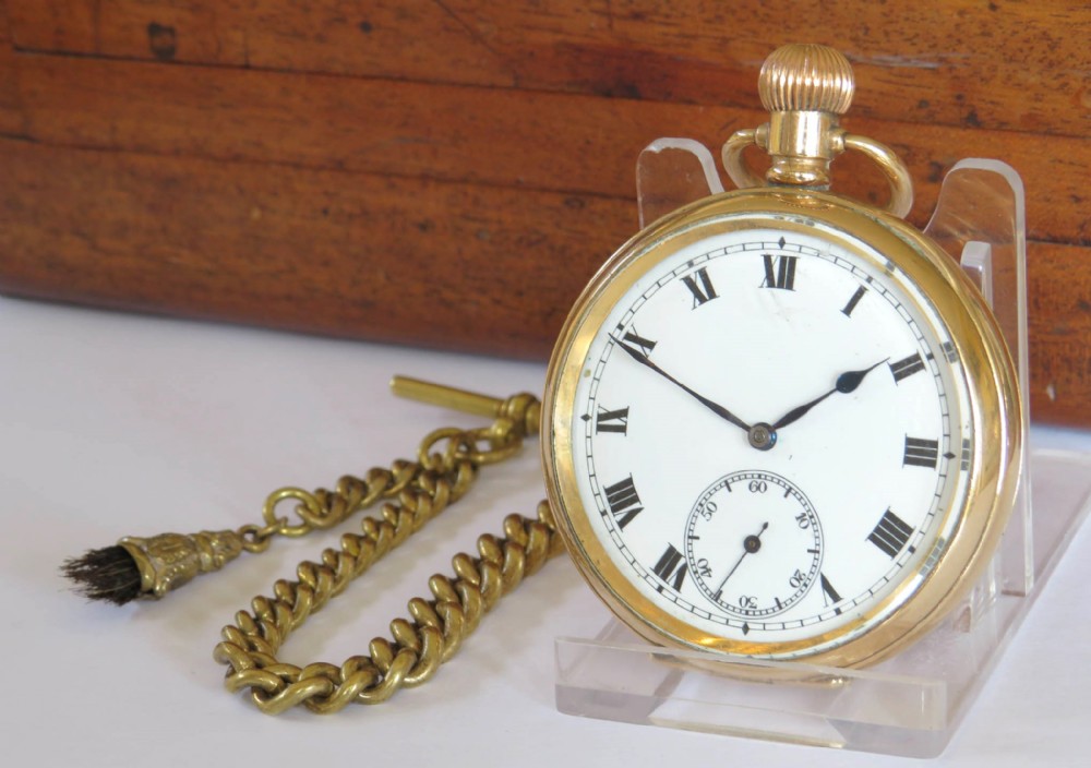 An antique 1920s gold-plated open-face pocket watch by Syren featuring a white enamel dial with Roman numerals, a sub-seconds dial, and an attached curb link chain with a tassel fob.