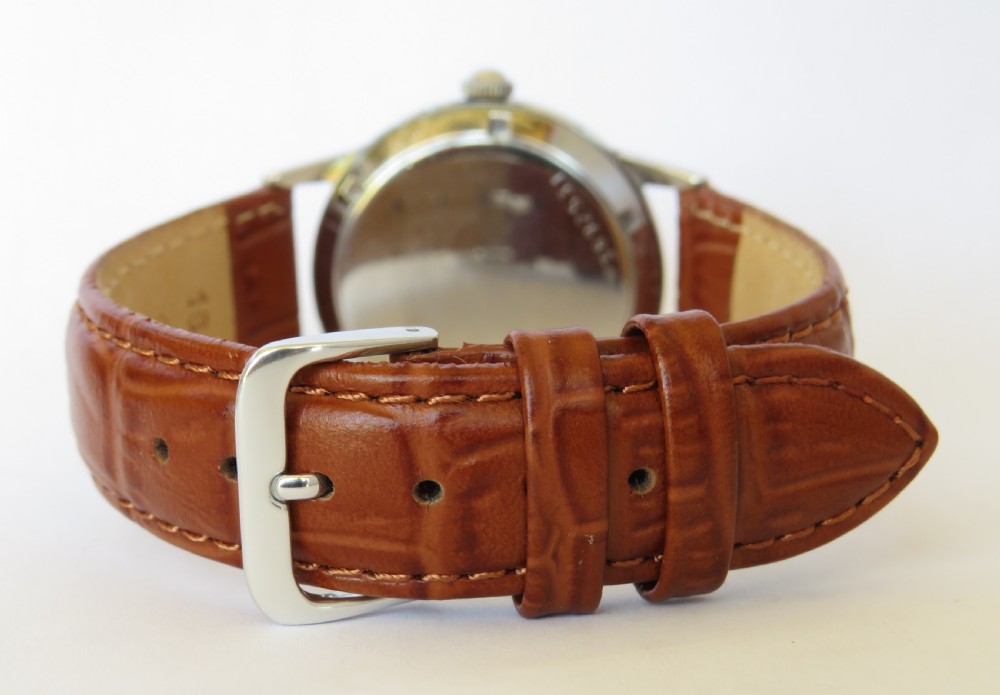 A 1950s Eterna-Matic gents wrist watch featuring a champagne dial, gold-tone hour markers, date aperture, and a brown leather strap. View IV