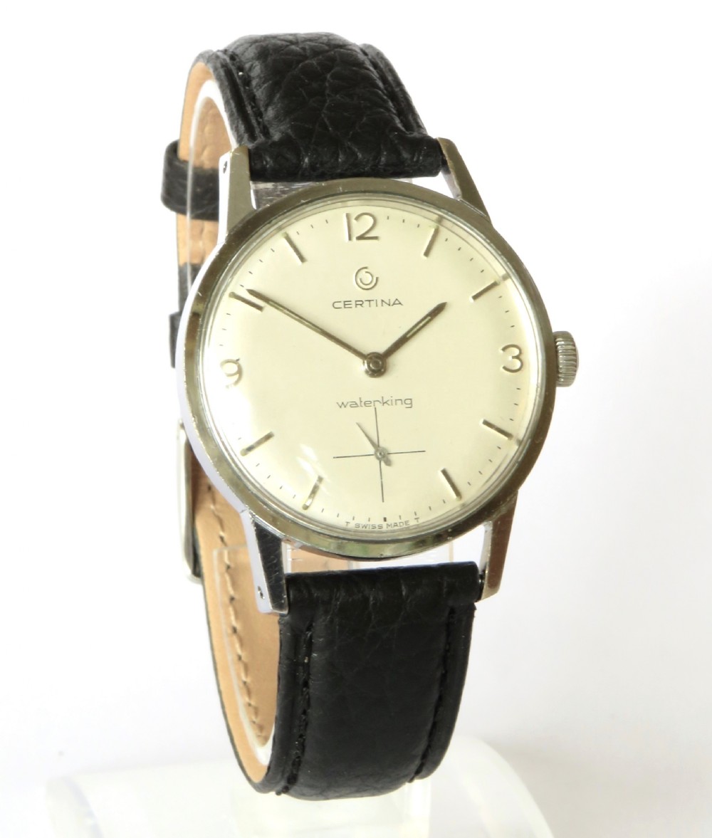 A 1968 Certina Waterking gents wristwatch featuring a silver-tone case, cream dial with Arabic quarter numerals, crosshair sub-seconds dial, and black textured leather strap. View II