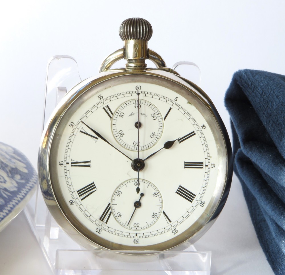 An antique open-faced silver chronograph pocket watch featuring a white enamel dial with Roman numerals and dual sub-dials. View II