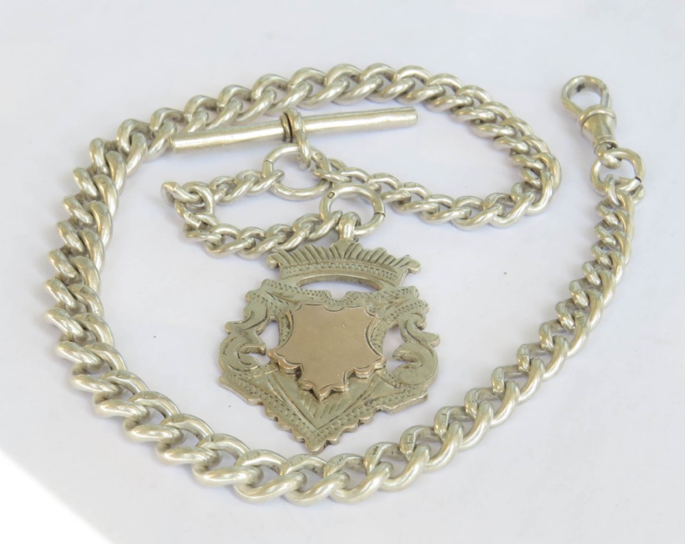 An antique sterling silver Albert watch chain with curb links, a T-bar, swivel clasp, and an engraved shield fob featuring rose gold detail.