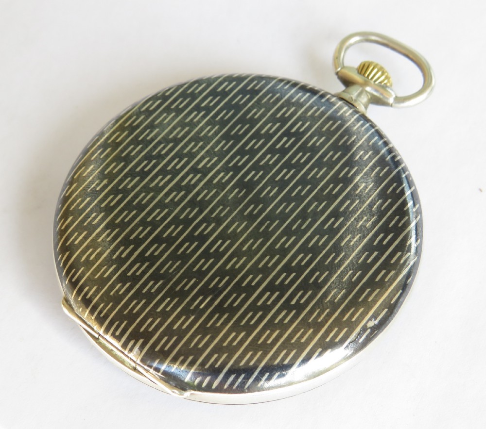 An open-face 1930s silver pocket watch featuring a patterned niello bezel, cream dial, black Arabic numerals, and a sub-seconds dial at six oclock. View V