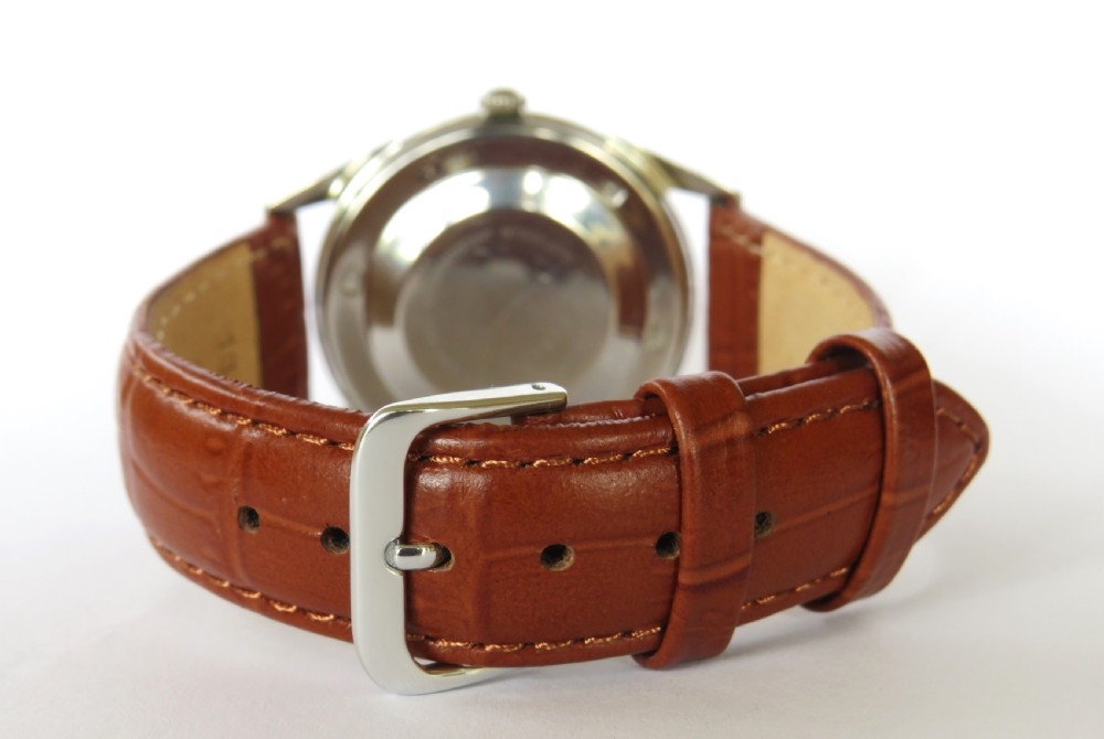 A vintage gentlemens Bucherer automatic wrist watch featuring a champagne dial with baton indices, date window, silver-toned metal case, and textured brown leather strap. View V