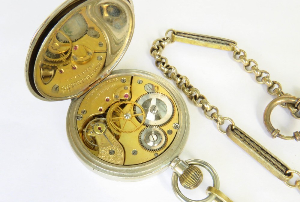 An antique silver-tone Octava 8-day open-face pocket watch featuring a white enamel dial with black Arabic numerals and an attached chain. View V