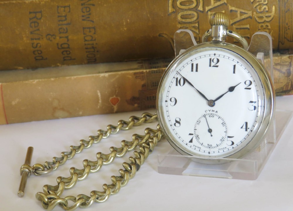 A 1920s Cyma open-face pocket watch featuring a white enamel dial with black Arabic numerals, a sub-seconds dial, and an attached link chain with a T-bar.