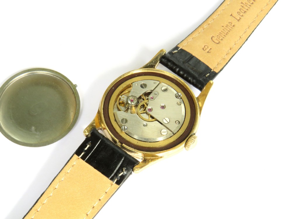 A 1950s gents Berg Parat wristwatch featuring a gold-plated case, a black dial with gold numerals, and a black leather strap. View IV