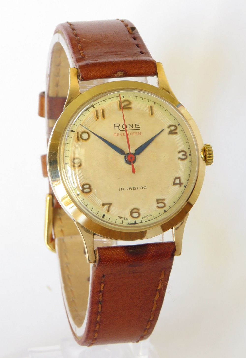 A 1960s gents 9ct gold Rone Seventeen wristwatch featuring a champagne dial with gold Arabic numerals and a brown leather strap. View II