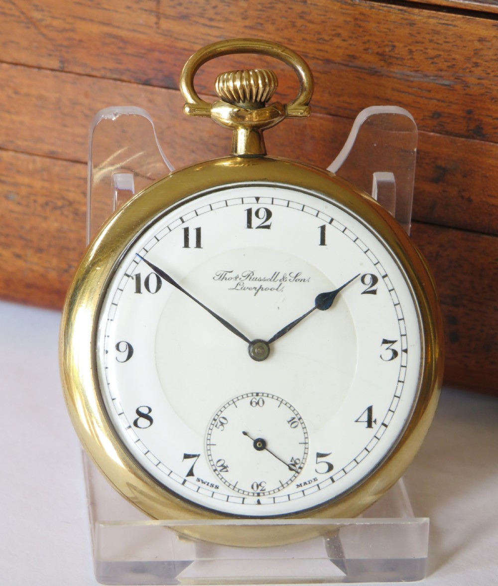 A 1930s gold-tone open-face pocket watch featuring a white enamel dial, black Arabic numerals, a sub-seconds dial at six oclock, and signature marked Thomas Russell and Son Liverpool. View II