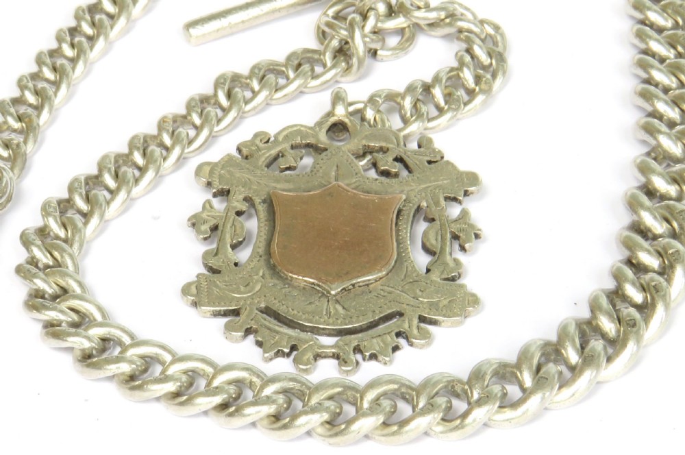 An Edwardian sterling silver Albert pocket watch chain featuring curb links, a T-bar fastener, a swivel clasp, and a decorative shield-shaped fob with a rose gold cartouche. View II