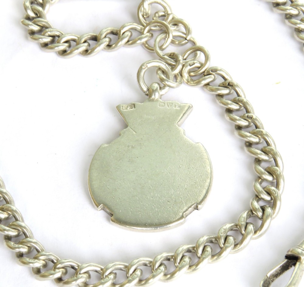 An antique sterling silver double Albert pocket watch chain featuring curb links, two swivel clasps, a central T-bar, and an engraved shield fob medallion topped with a crown motif. View III