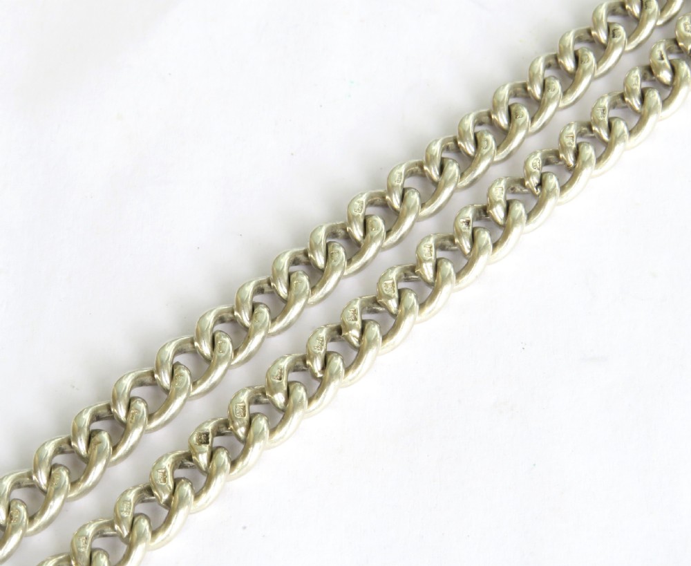 An antique sterling silver double Albert pocket watch chain featuring curb links, two swivel clasps, a central T-bar, and an engraved shield fob medallion topped with a crown motif. View IV