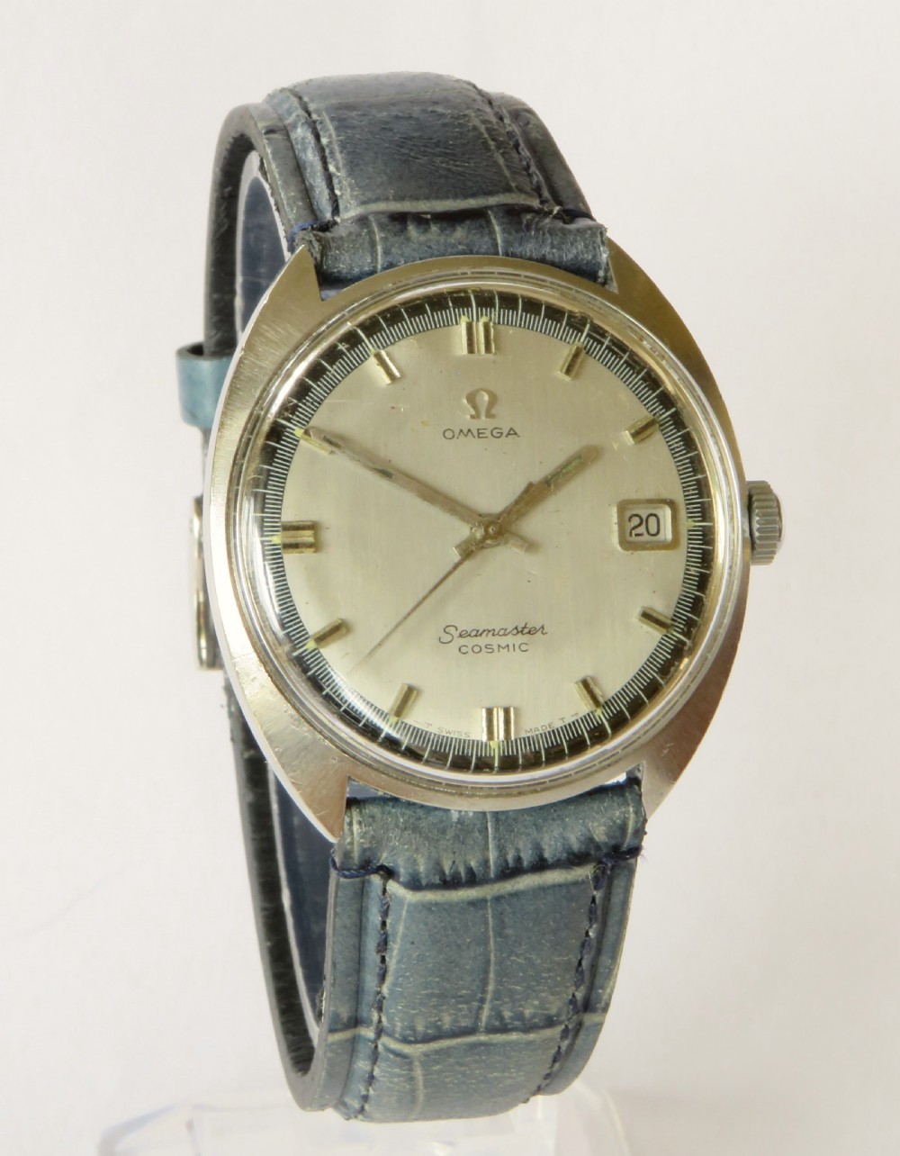 A 1960s gents Omega Seamaster Cosmic wristwatch featuring a stainless steel cushion case, silver dial with date display, and a blue leather strap. View II