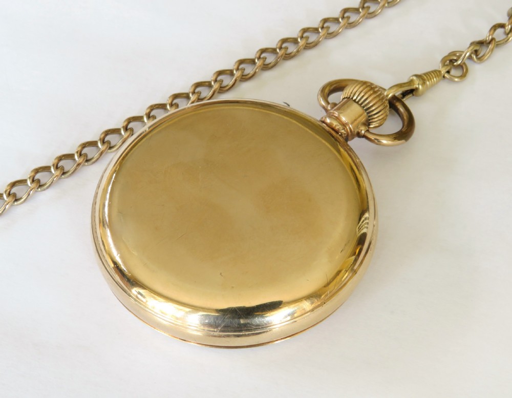 An antique gold-toned open-face pocket watch featuring a white enamel dial with black Roman numerals, blued steel hands, a subsidiary seconds dial, and an attached gold-toned Albert chain. View V