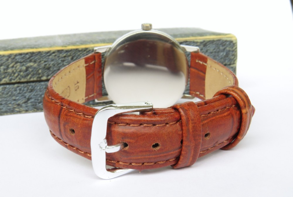 A 1966 Omega Geneve wristwatch featuring a round silver-toned dial, black baton indices, and a textured brown leather strap. View VI