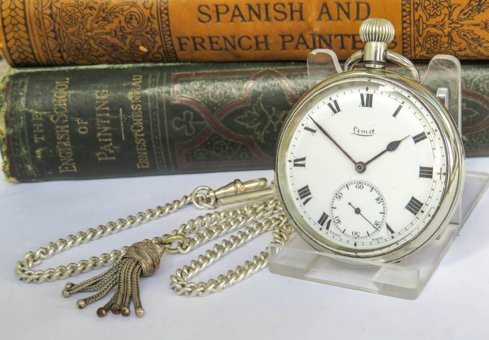 An open-face silver-toned pocket watch featuring a white enamel dial, black Roman numerals, a sub-seconds dial, and an attached curb link chain with a tassel fob.
