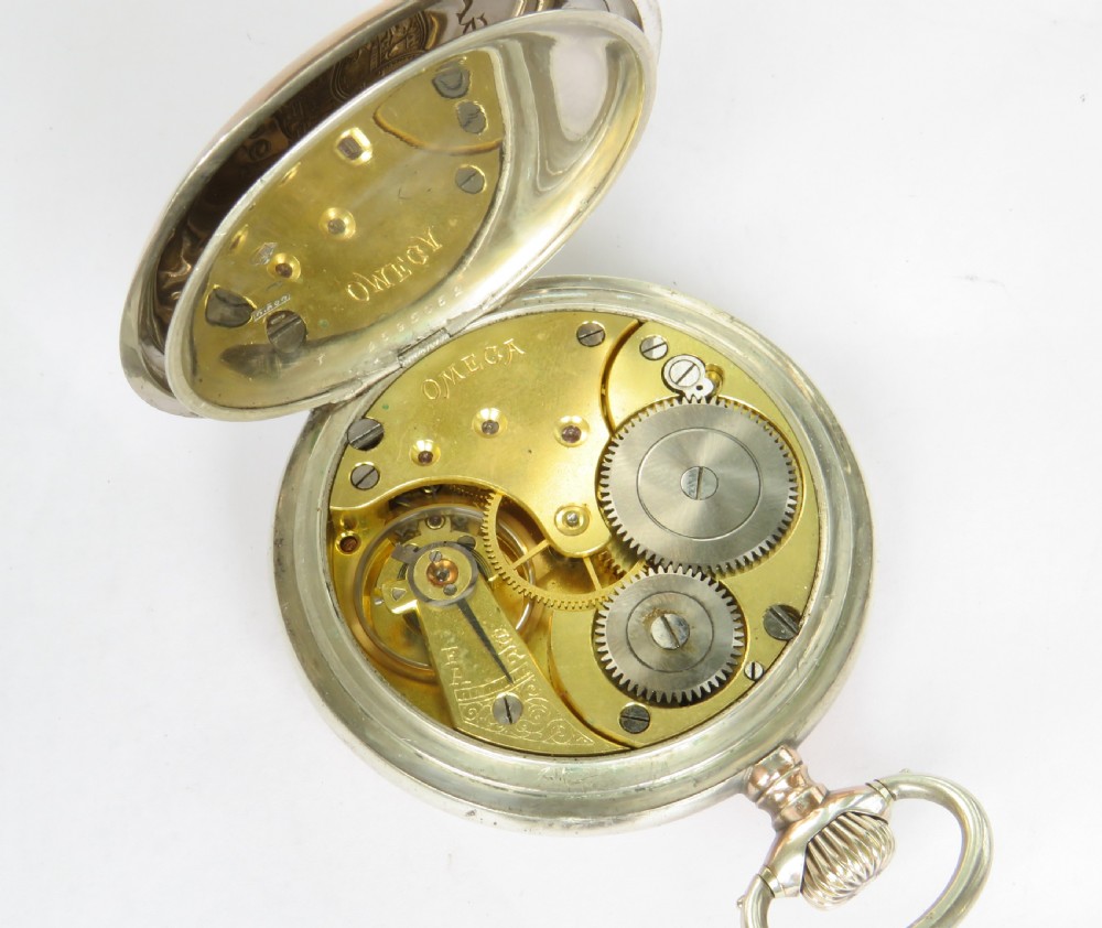 An antique open-face silver pocket watch featuring a white enamel dial with black Arabic numerals and a subsidiary seconds dial at six oclock. View V